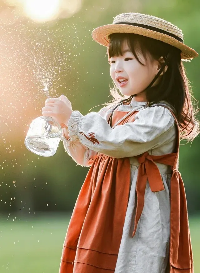 戴草帽的孩子在暖色逆光中吹泡泡